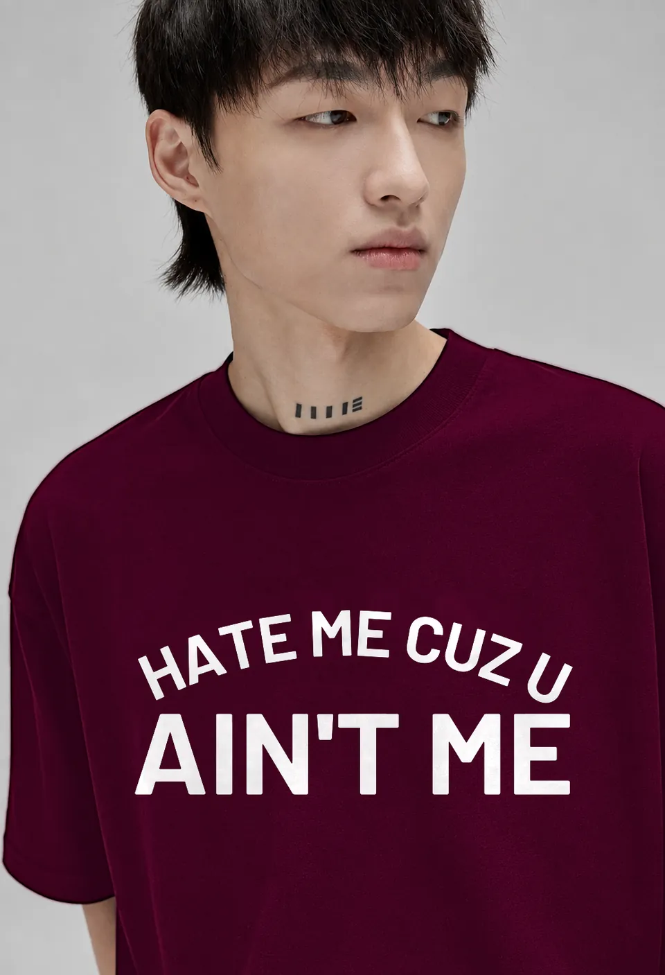 Close-up of the white arched Hate Me Cuz U Ain't Me lettering on a burgundy oversized t-shirt