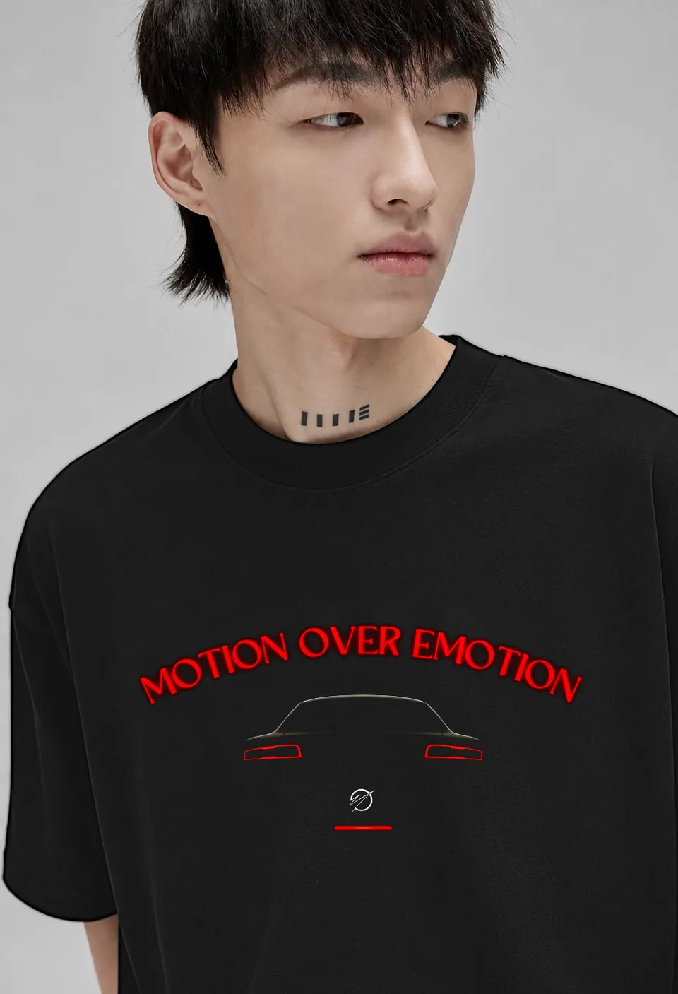 Close-up of the red neon Motion Over Emotion arc above a car silhouette with glowing tail lights on a black oversized t-shirt