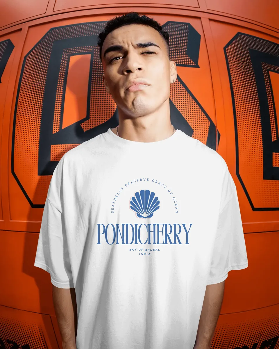 Model wearing the white Pondicherry oversized t-shirt by an orange wall