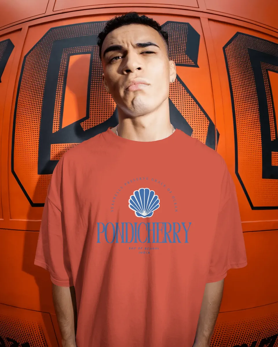 Model wearing the red Pondicherry oversized t-shirt by an orange wall